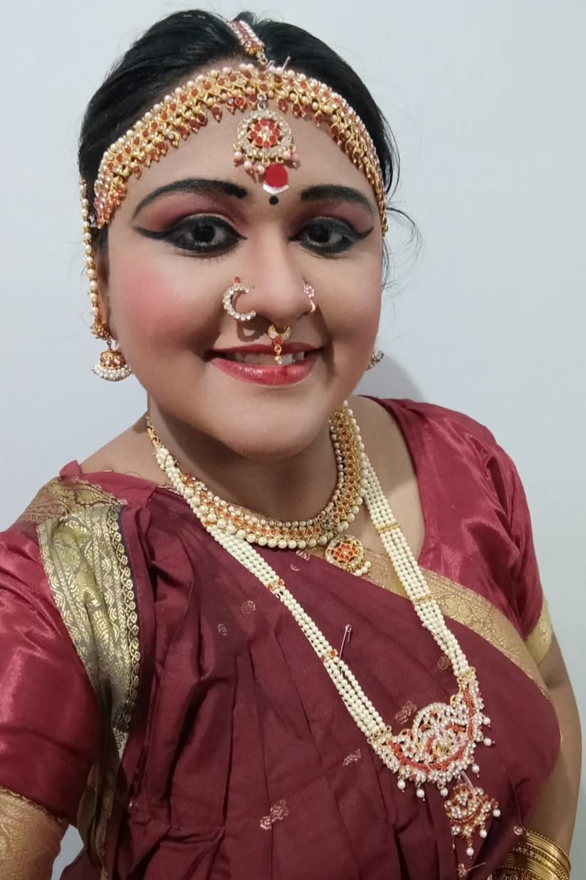 A girl wearing a Bharatnatyam outfit of maroon colour.